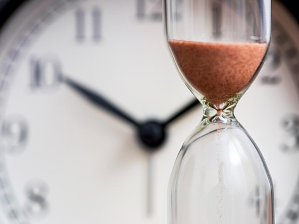 Concept of time pressure with clock in background and egg timer in foreground